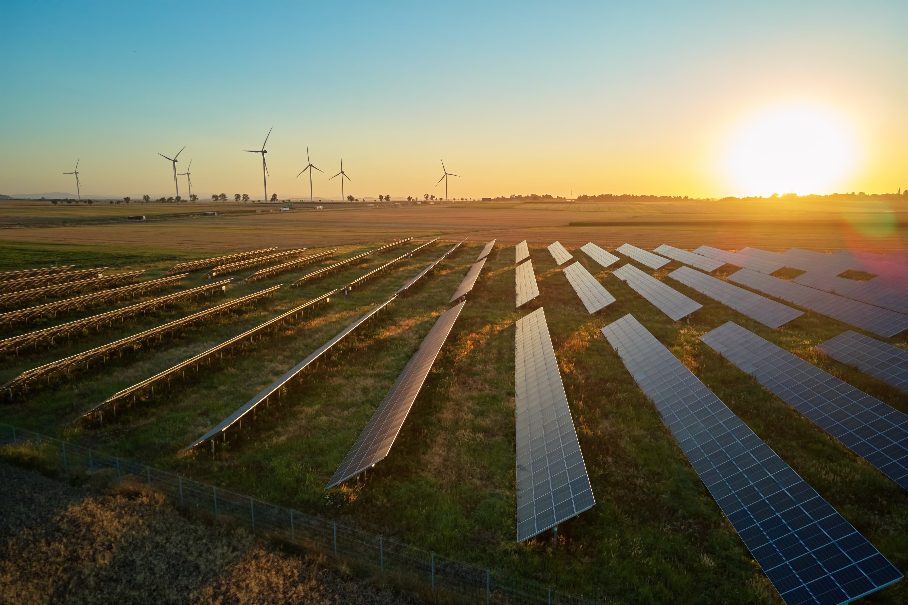 Solar installation and wind turbines at sunset